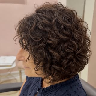 A curly Amani Scalp Illusion topper that blends seamlessly for natural volume, movement, and confide